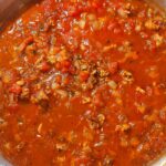 Marinara sauce with Italian sausage in a skillet.