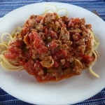 Homemade Italian sausage on top of a plate of spaghetti.