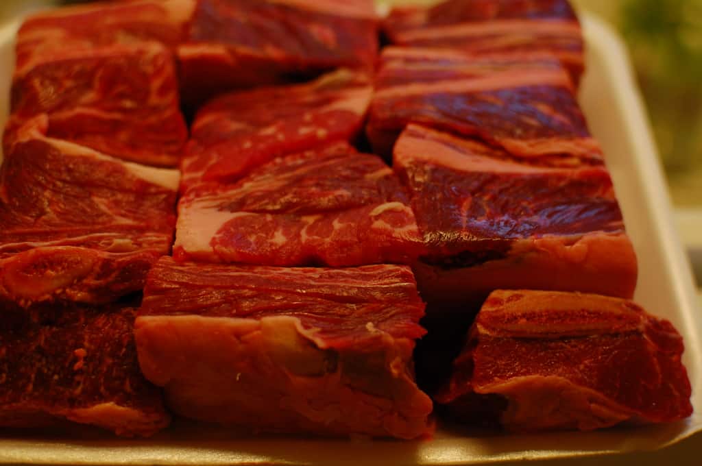 Beef short ribs raw on a sheet pan.