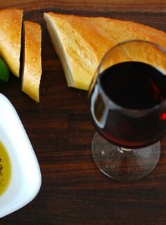 French baguette, glass of red wine and a plate of seasoned olive oil.
