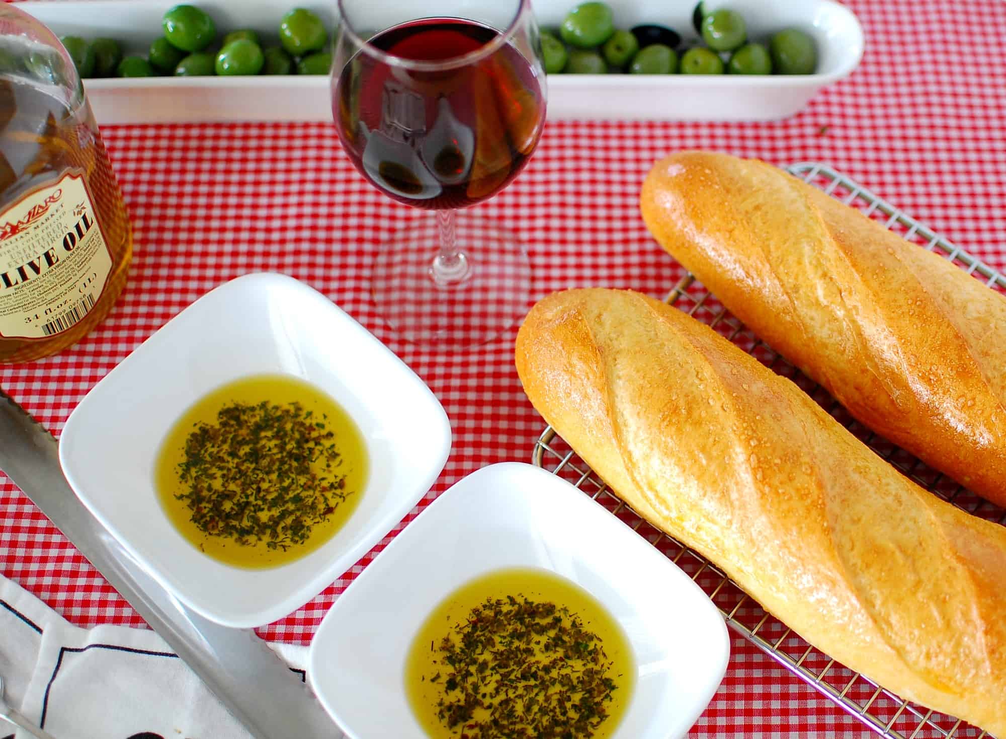 Overhead view of 2 French baguettes, and two plates of seasoned olive oil.