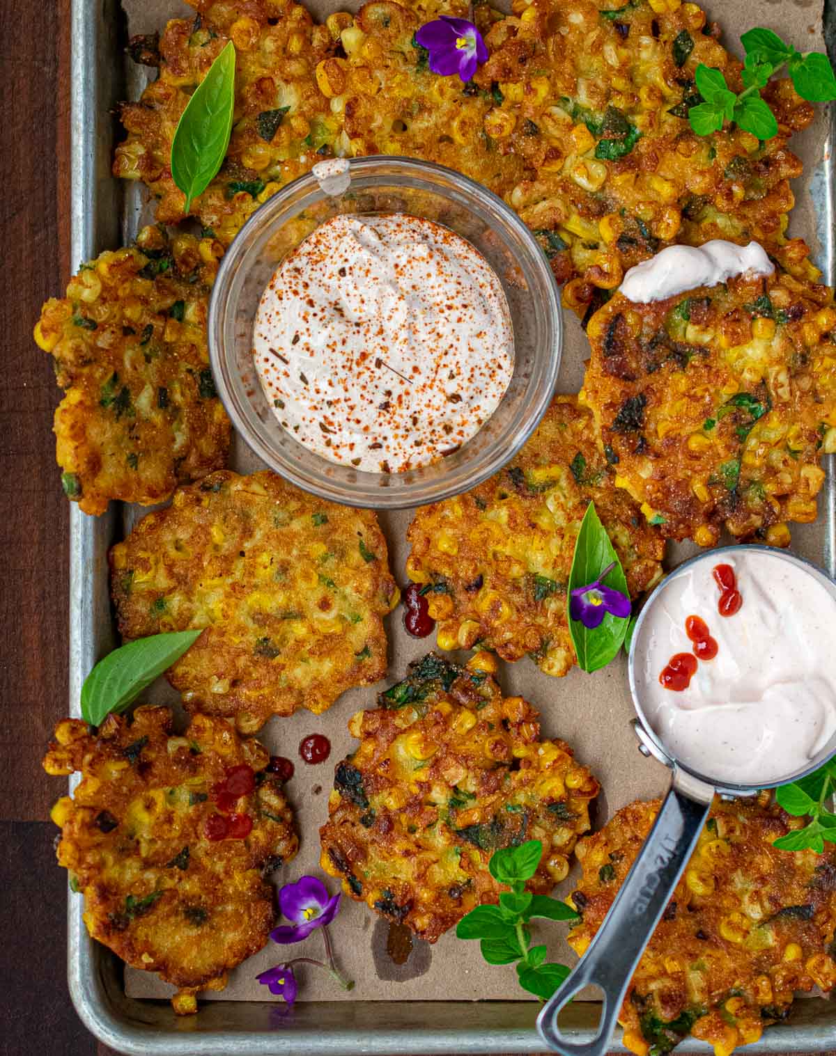 A tray of corn fritters and 2 sour cream dipping sauces.