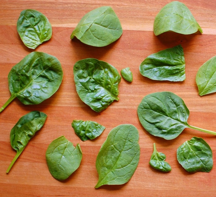 Spinach leaves on a cutting board.