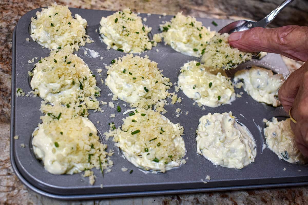 Panko bread crumbs being added over the crab batter.