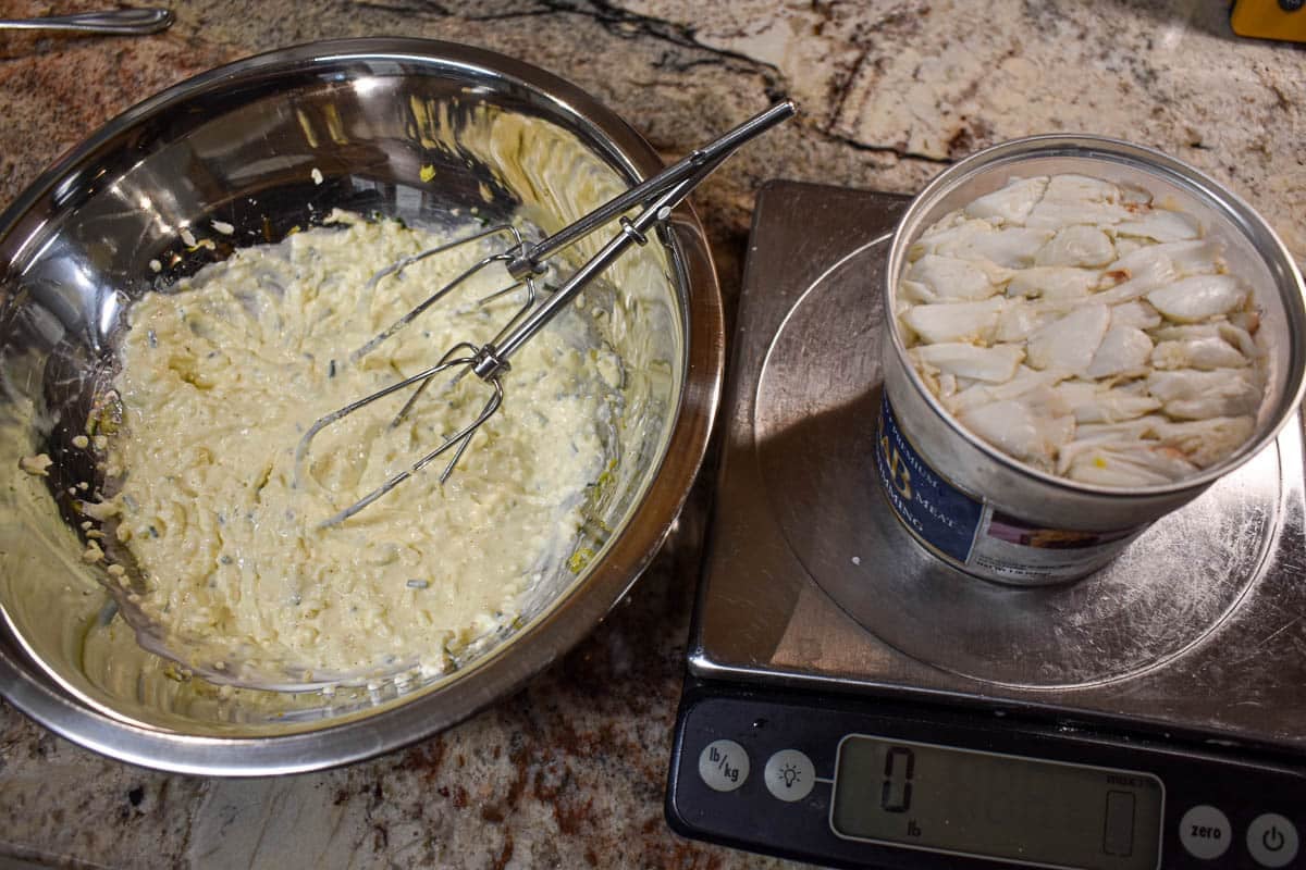 A bowl with a mixture of cream cheese that has been beaten with a hand mixer.