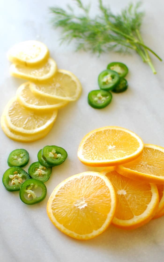 Slices of oranges and lemon with dill sprigs and jalapeno.