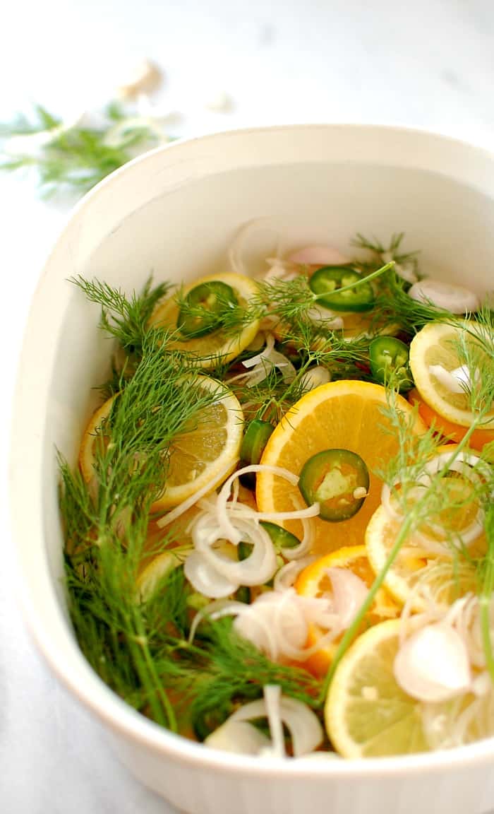 Casserole dish with citrus slices, onions and dill weed.