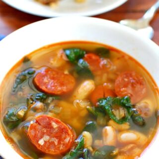 Spinach and chorizo soup in a white bowl.