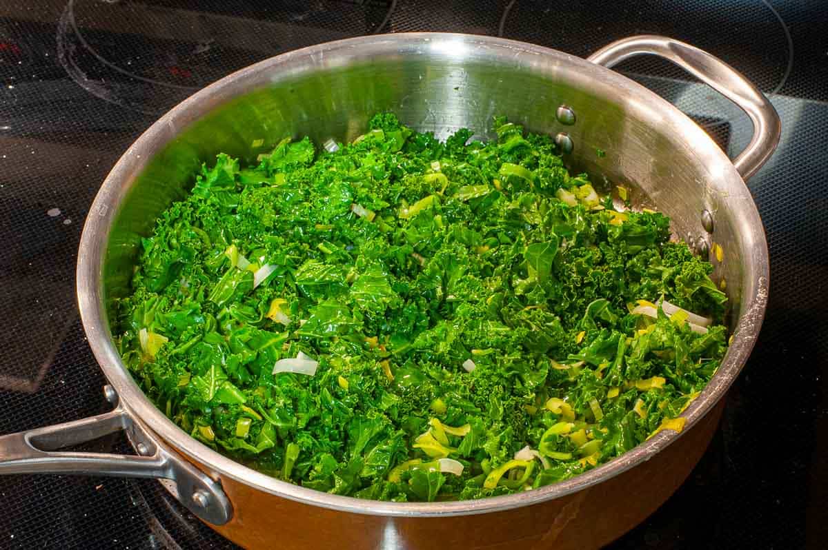 Skillet on the stove with leeks and kale.