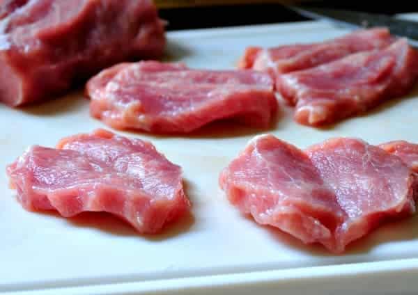 Butterflied pork on a plastic cutting board.