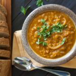 Lentil soup in a bowl with rye bread.