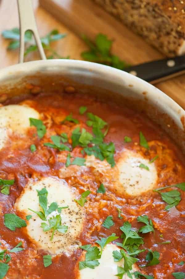 Shakshuka with good, crusty bread. African and Mid eastern poached eggs in spicy tomato sauce. A treat for breakfast, lunch, or dinner. | joeshealthymeals.com