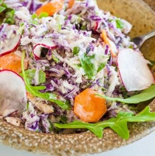 Tuna salad in a bowl containing cabbage, radish, and carrots.