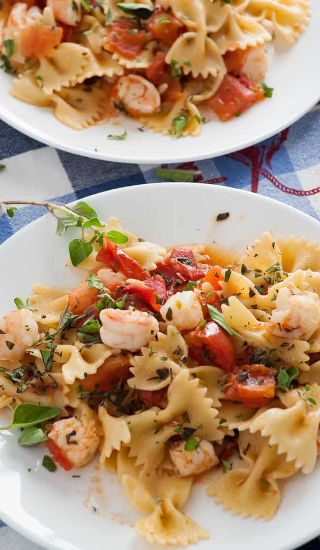 Two plates of pasta with shrimp.