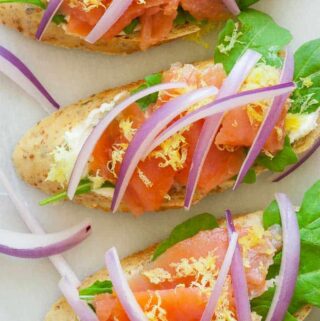 Smoked salmon appetizer with flavored cream cheese, arugula, lemon zest, and topped with sliced red onion. Only 82 calories for each. | joeshealthymeals.com