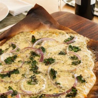 White pizza sauce pizza on parchment ready to be sliced. | joeshealthymeals.com
