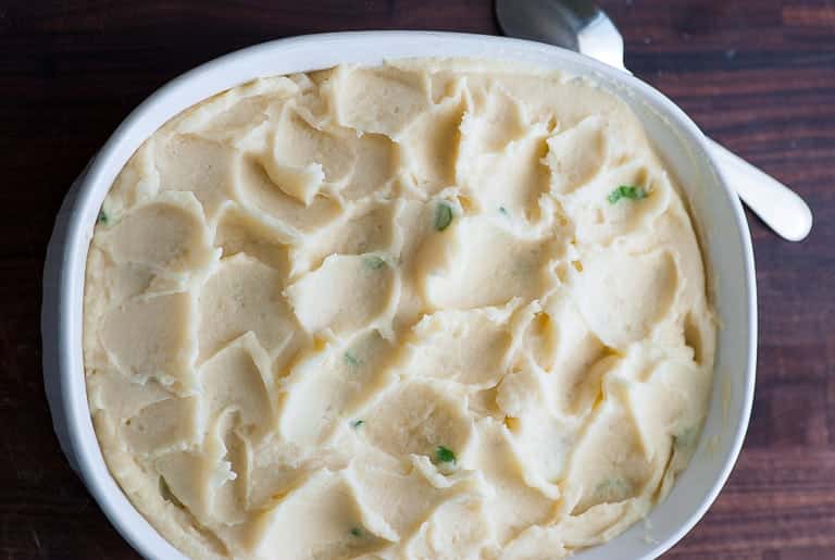 Cooked mashed potatoes in a casserole dish ready to be covered and refrigerated.