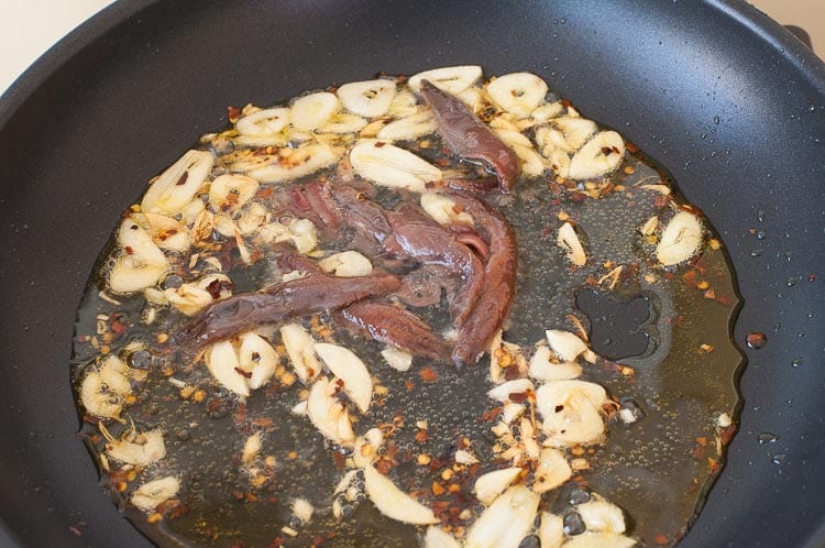 Anchovies added to the skillet with the garlic.