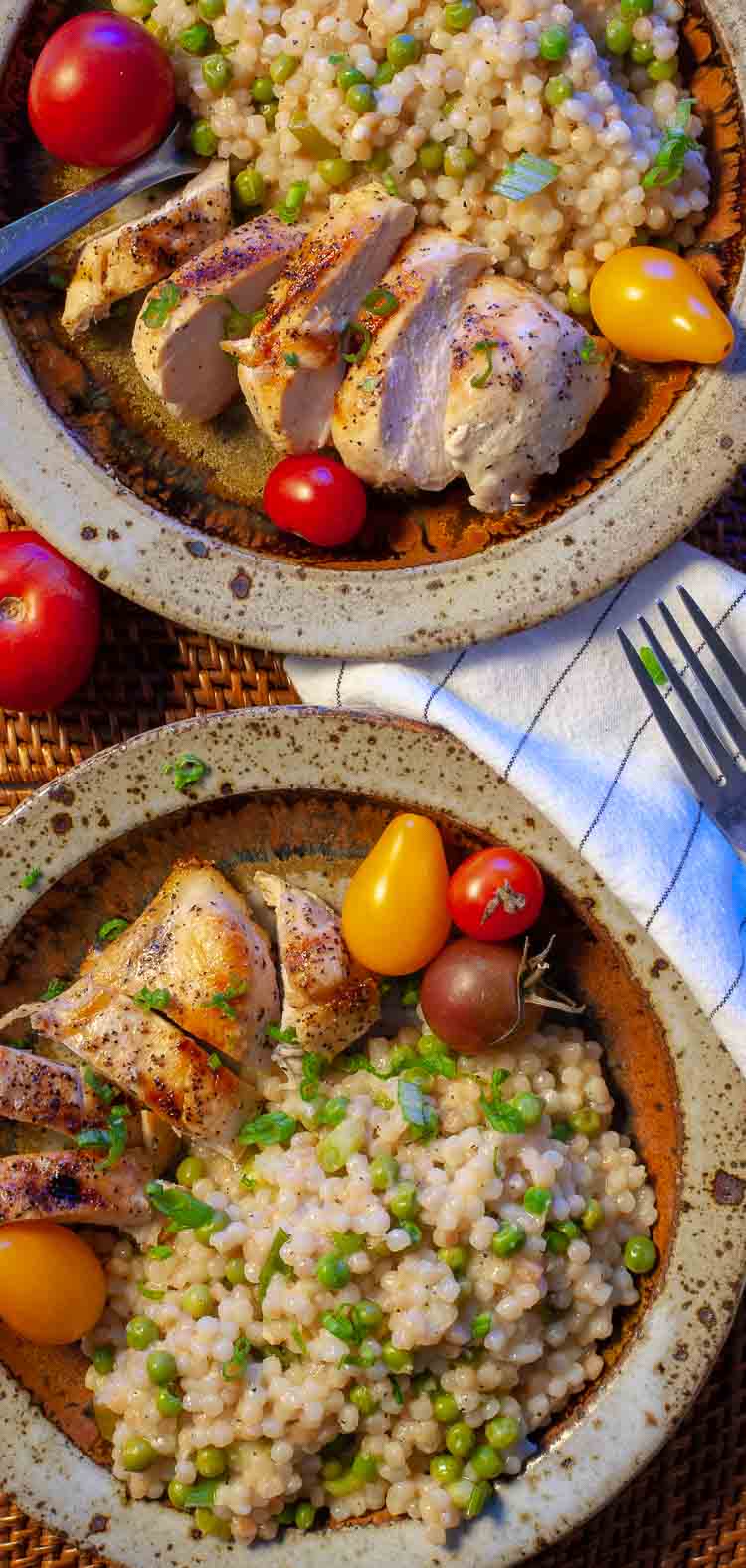 Couscous in a bowl with chicken and grape tomatoes.