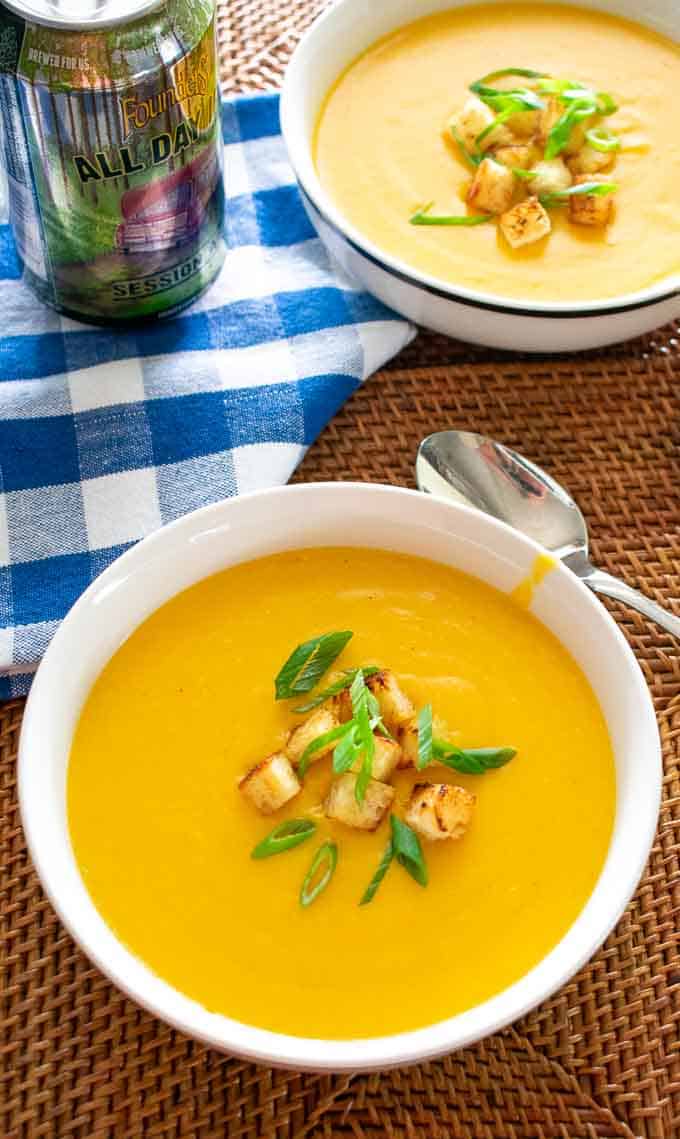 Beer cheese soup in a bowl with croutons and green onion.