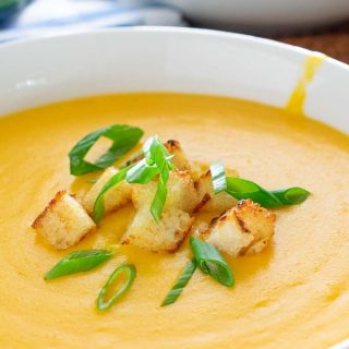 Close-up of beer cheese soup with croutons and green onion.