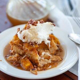 A plate of pumpkin bread pudding with whipped cream.