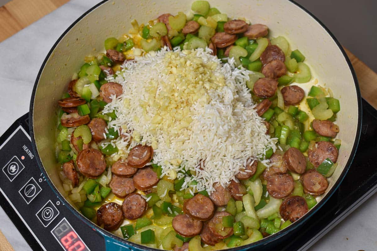 White rice and garlic added to the skillet.