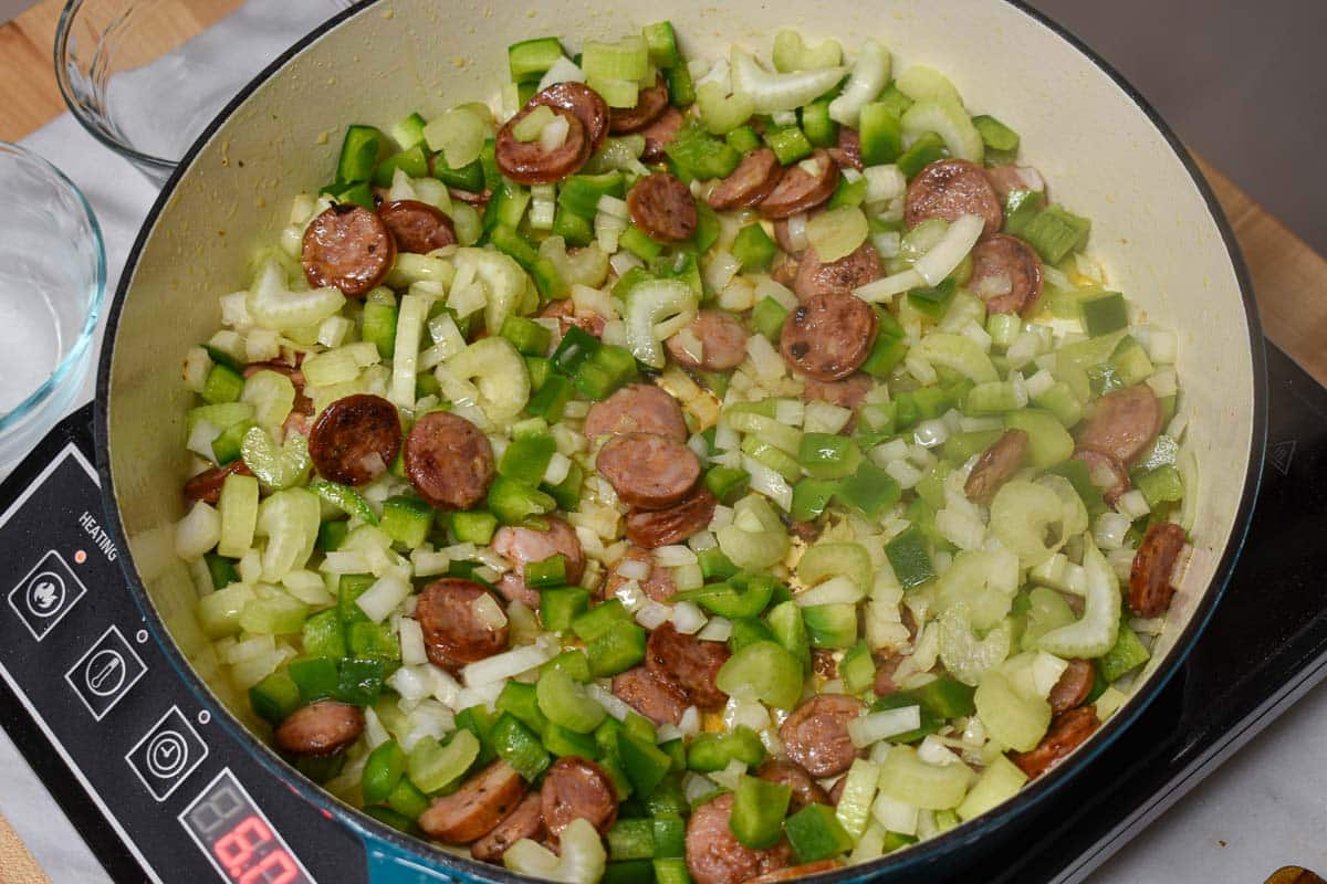 The holy trinity of onion, celery, and green pepper added to the Dutch oven.