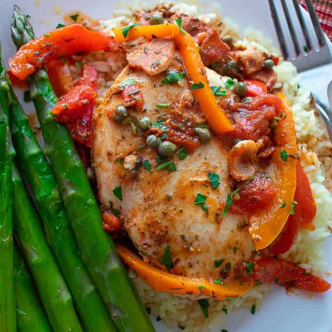 Close up view of chicken breast and bell peppers over rice.