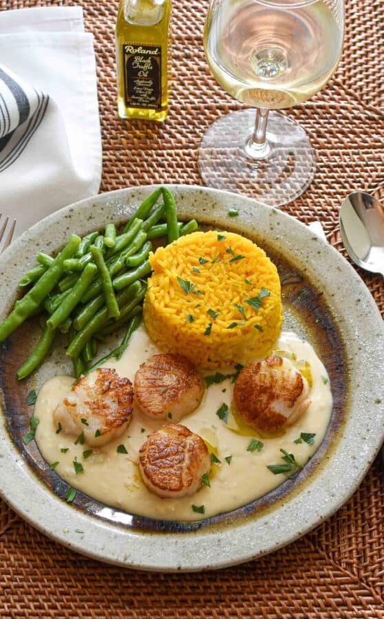 Plate of scallops and lobster sauce with rice and green beans.