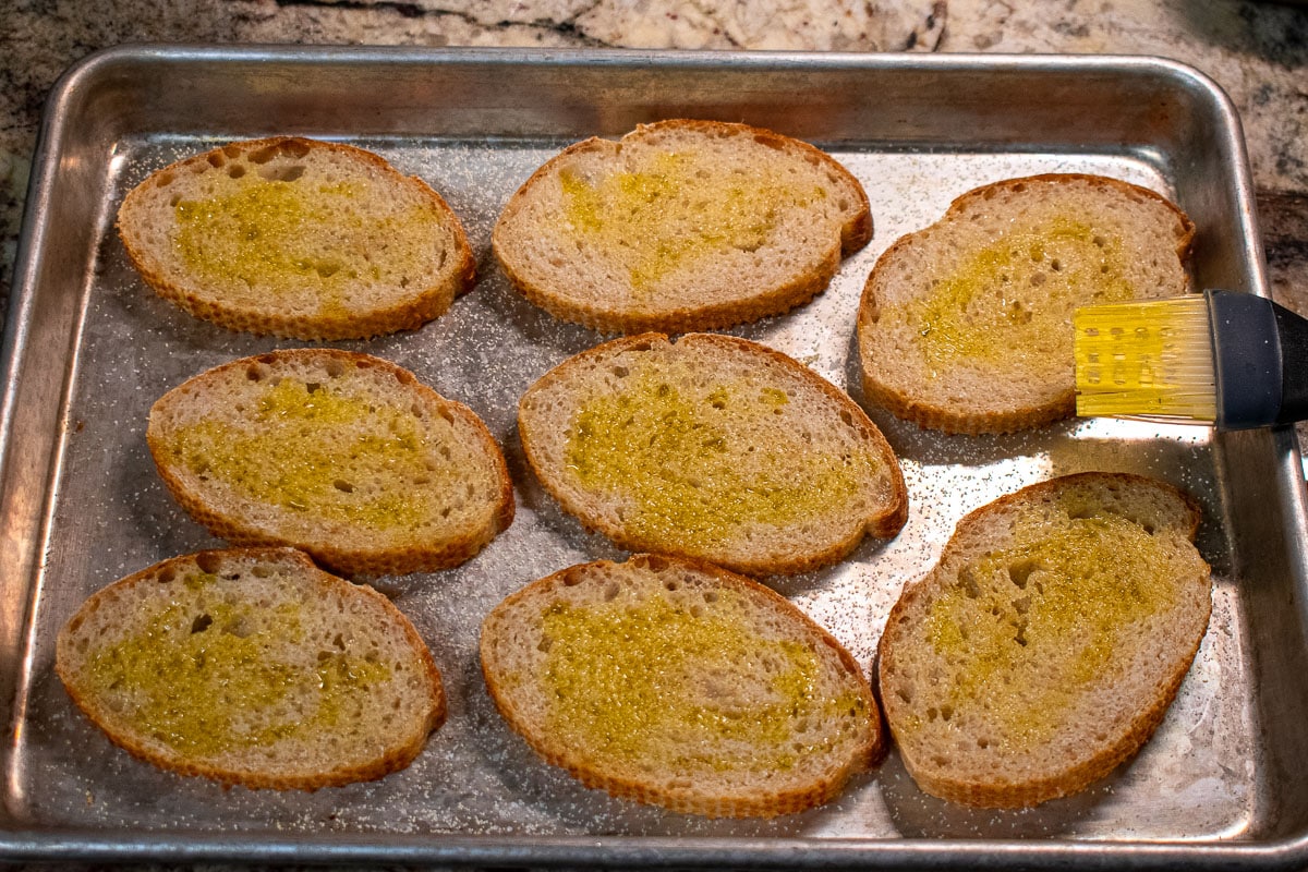 Bread slices being prepared on a sheet pan for the beef appetizers.