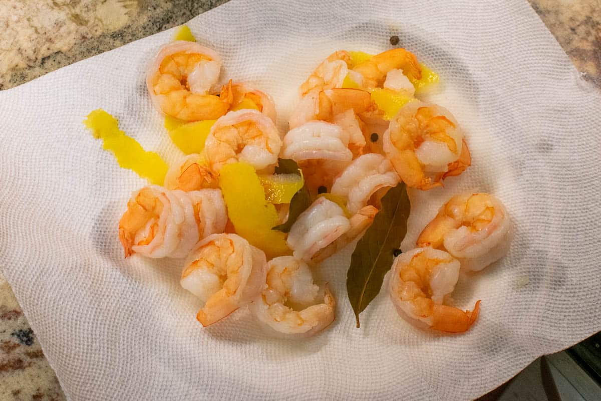 Poached shrimp on a paper towel lined plate.
