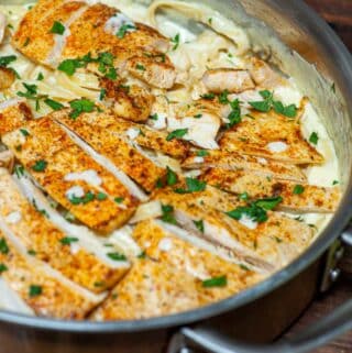 Skillet full of chicken, fettuccine, and alfredo sauce, ready to serve.