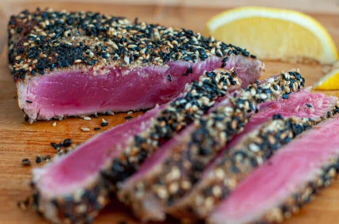 Ahi tuna steak being sliced on a cutting board.