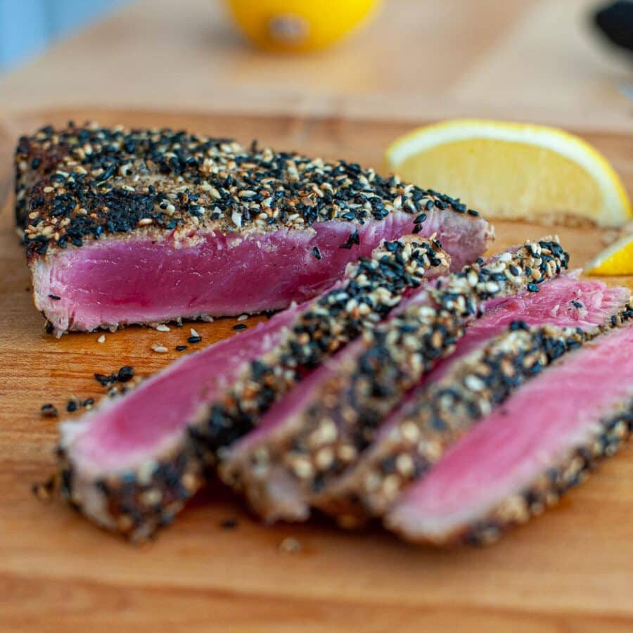Ahi tuna steak being sliced on a cutting board.