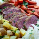 Cooked and sliced corned beef with side vegetables.