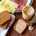 Russian dressing, corned beef, Swiss cheese, and rye bread on a table.