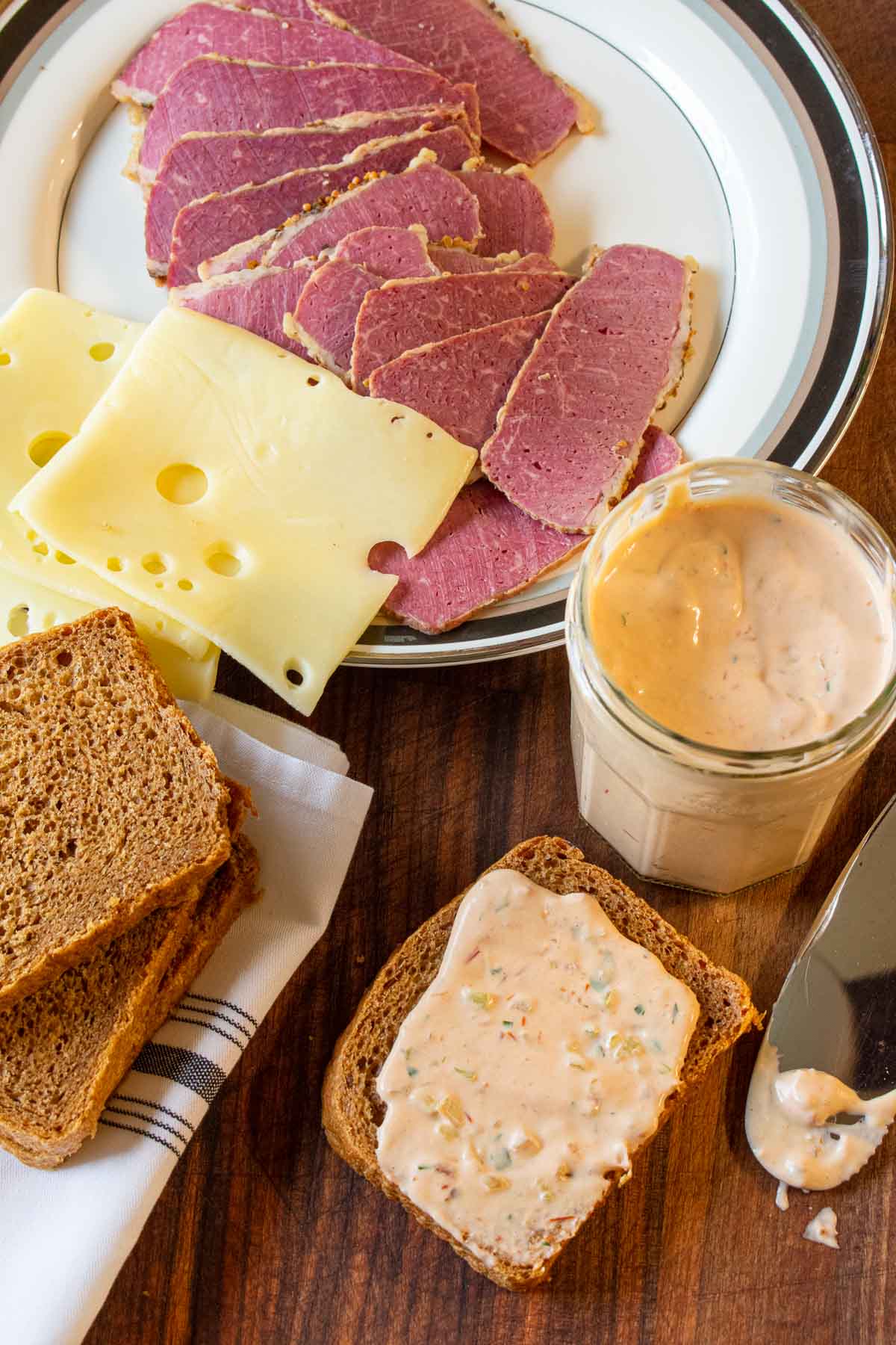 A plate of corned beef, swiss cheese, and bread with Russian dressing.