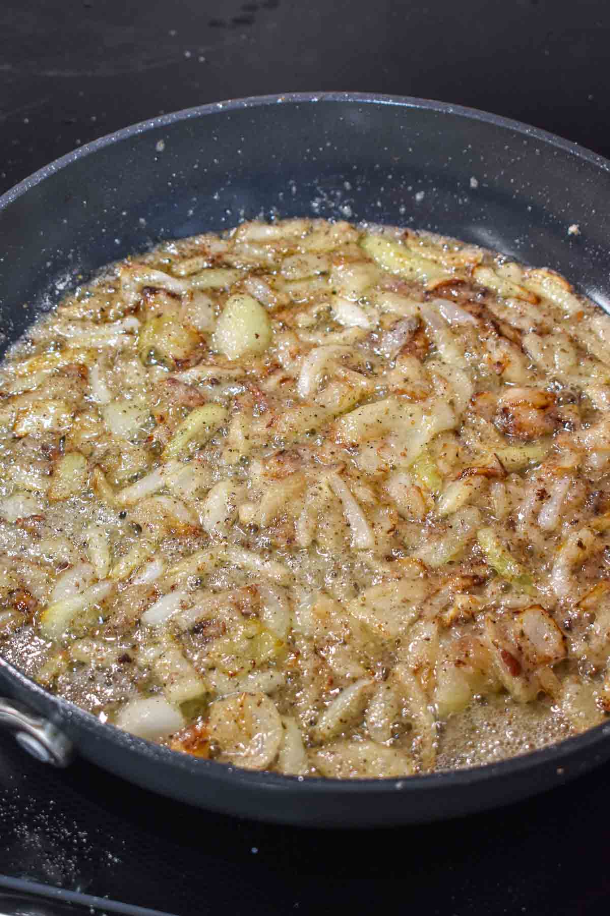 Cooked onions in a skillet with sugar and spices added.