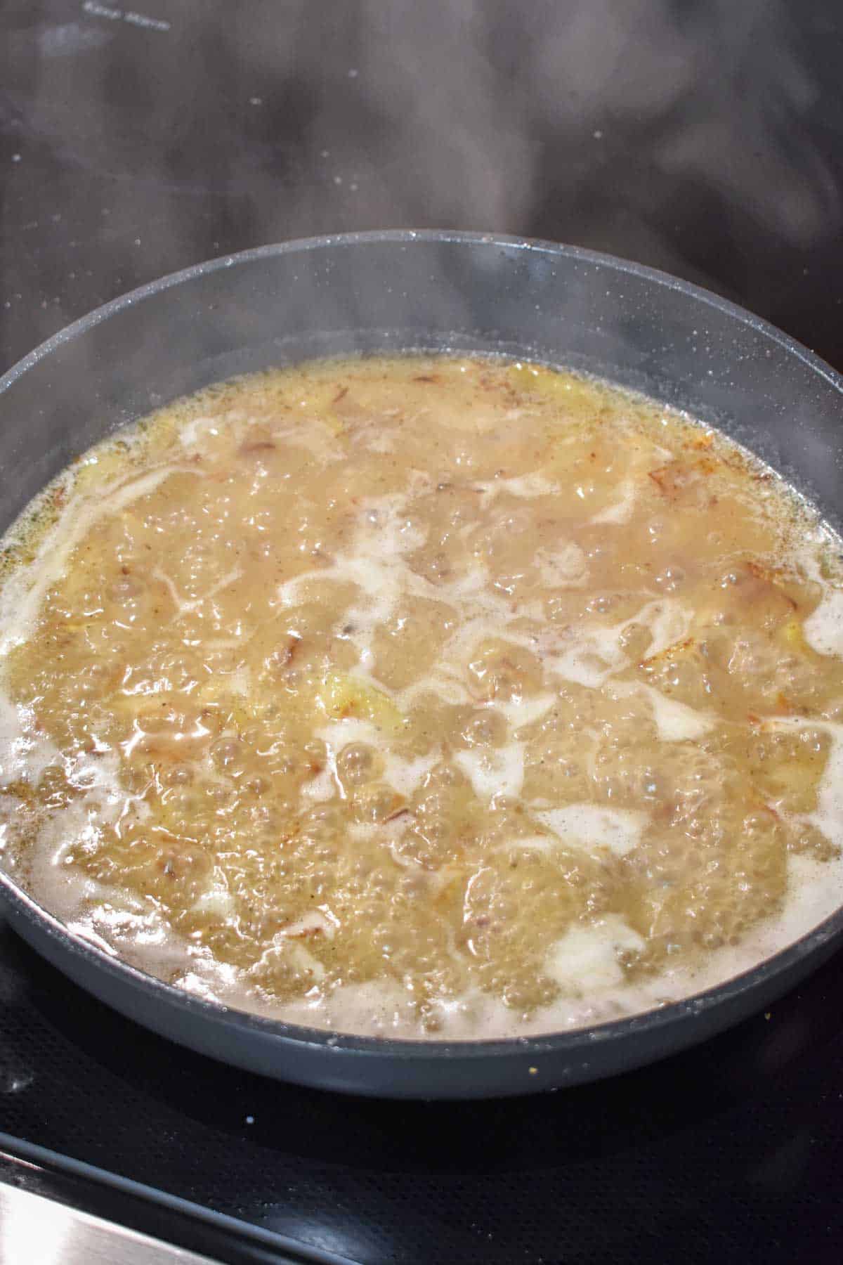 Sweet and sour sauce for German potato salad simmering in a skillet.